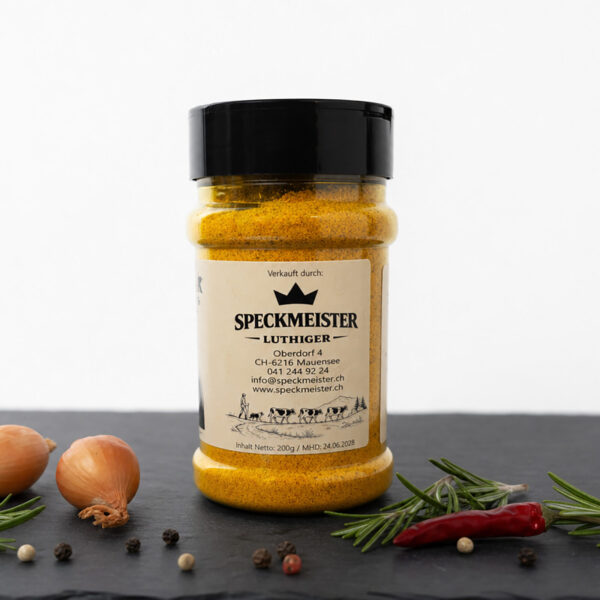 Gewürzdose Speckmeister Luthiger auf dunkler Fläche, umgeben von Chili, Rosmarin, Zwiebel und Pfefferkörnern.