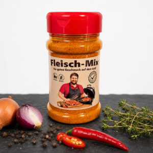 Fleisch‑Mix Gewürzdose mit Zwiebeln, Chili, Pfefferkörnern und Thymian auf dunkler Fläche.