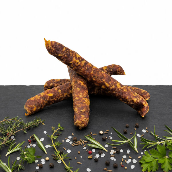 Buure Stäcke – traditionelle, luftgetrocknete Schweizer Fleischspezialität Rustikale Buure Stäcke auf dunkler Steinplatte mit Kräutern, Pfeffer, Salz und Gewürzen